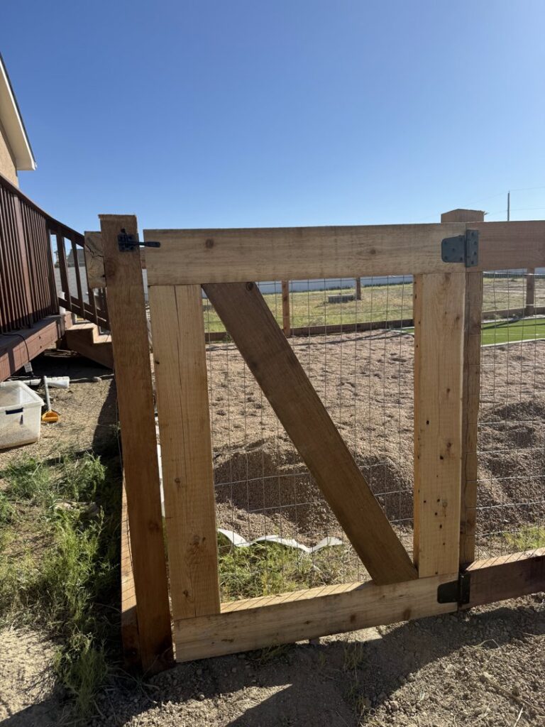 A wooden gate with wire mesh installed next to a deck by Pueblo Fence Co in Pueblo West, CO.