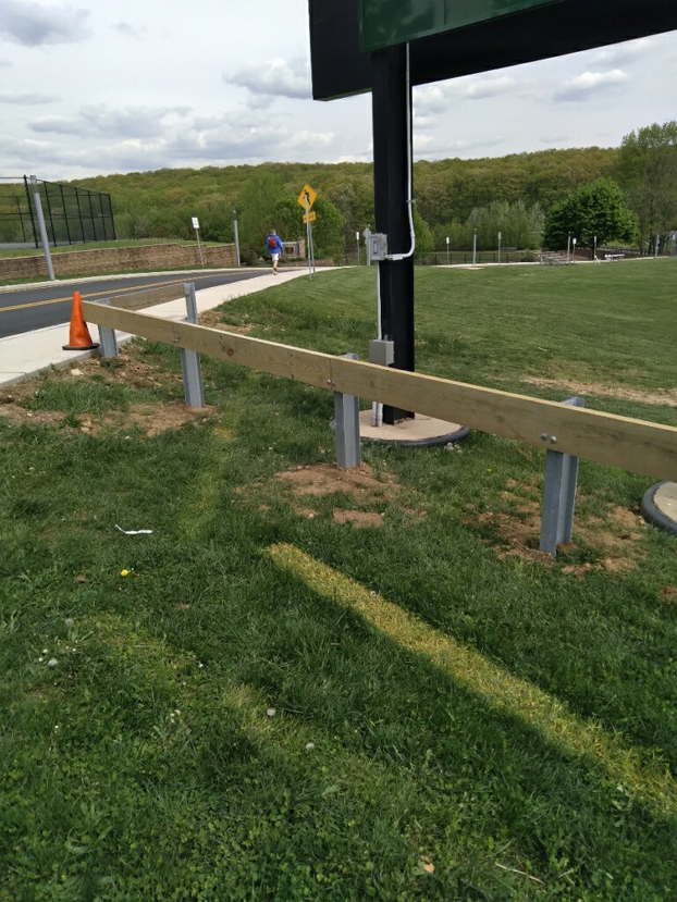 A sturdy wooden guardrail fence installed along a pathway in a grassy area by Fox Fence Enterprises Inc in Clifton, NJ.