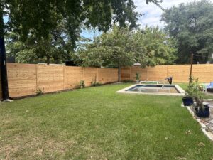 A wooden horizontal slat fence enclosing a backyard with a swimming pool by Landmark Fence & Deck Company in Saint Paul, MN.
