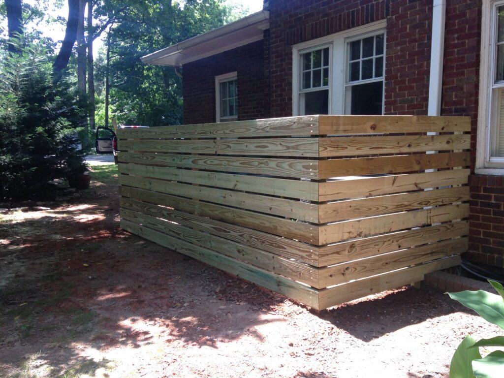 A wooden horizontal slat privacy screen installed next to a brick house by Timber Fencing in Charlotte, NC.