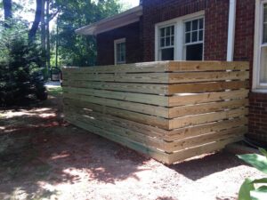 A wooden horizontal slat privacy screen installed next to a brick house by Timber Fencing in Charlotte, NC.