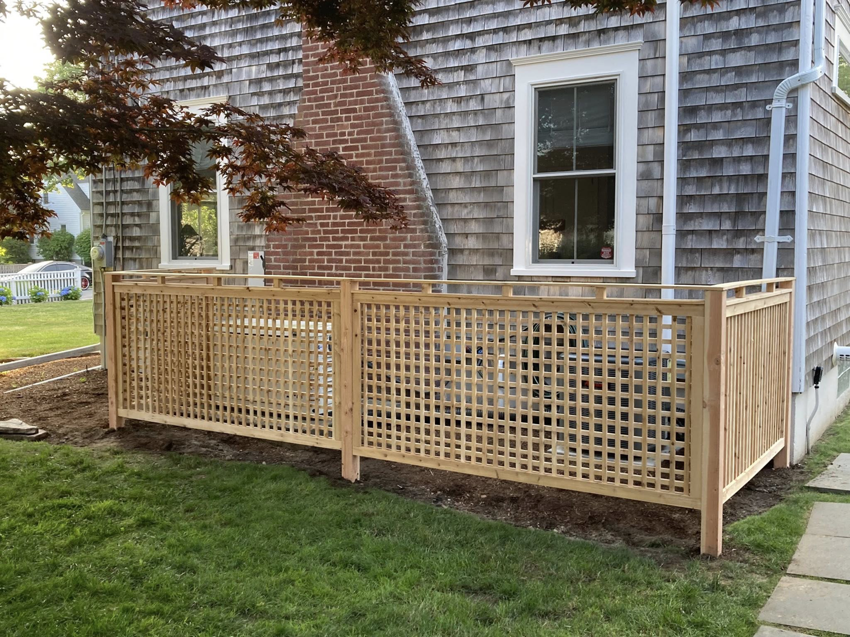 A decorative wooden lattice fence section installed next to a house by Profence in Leander, TX.