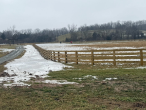 A newly installed wooden perimeter fence running alongside a gravel driveway by Richards Fencing in Lynnville, TN