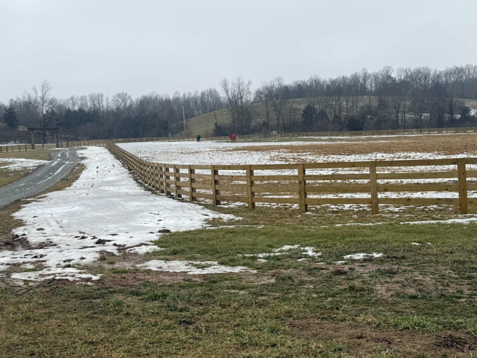 A newly installed wooden perimeter fence running alongside a gravel driveway by Richards Fencing in Lynnville, TN