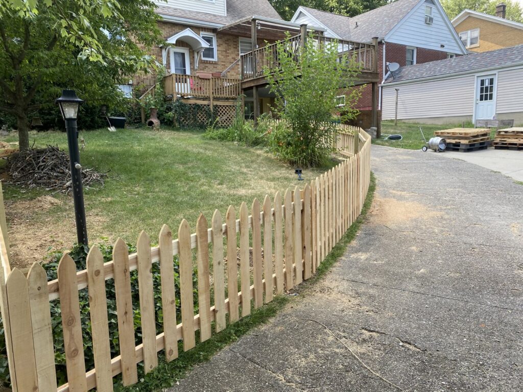 A charming wooden picket fence installed along a driveway by Petty Fence Company LLC in Evansville, IN.