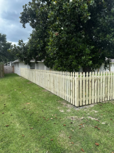 A newly installed wooden picket fence running along the side of a house by J&L Fence in Zolfo Springs, FL.