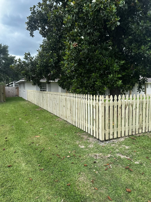A newly installed wooden picket fence running along the side of a house by J&L Fence in Zolfo Springs, FL.