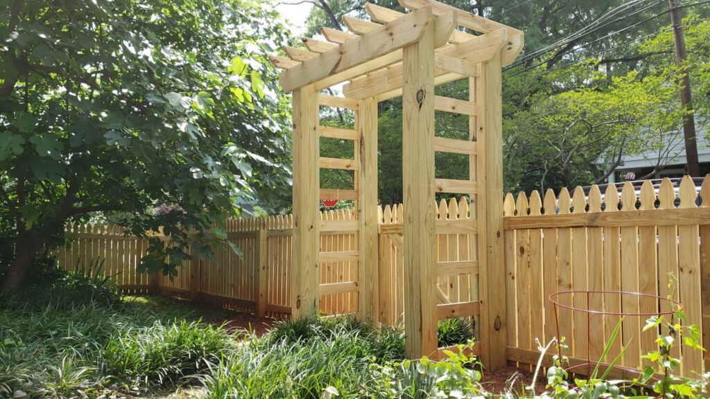 A wooden picket fence with an integrated wooden arbor and gate installed by Timber Fencing in Charlotte, NC.