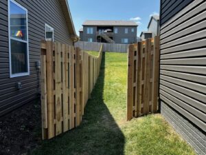 A newly installed wooden picket fence in a residential backyard by Custom Vinyl Fabrication in Omaha, NE.