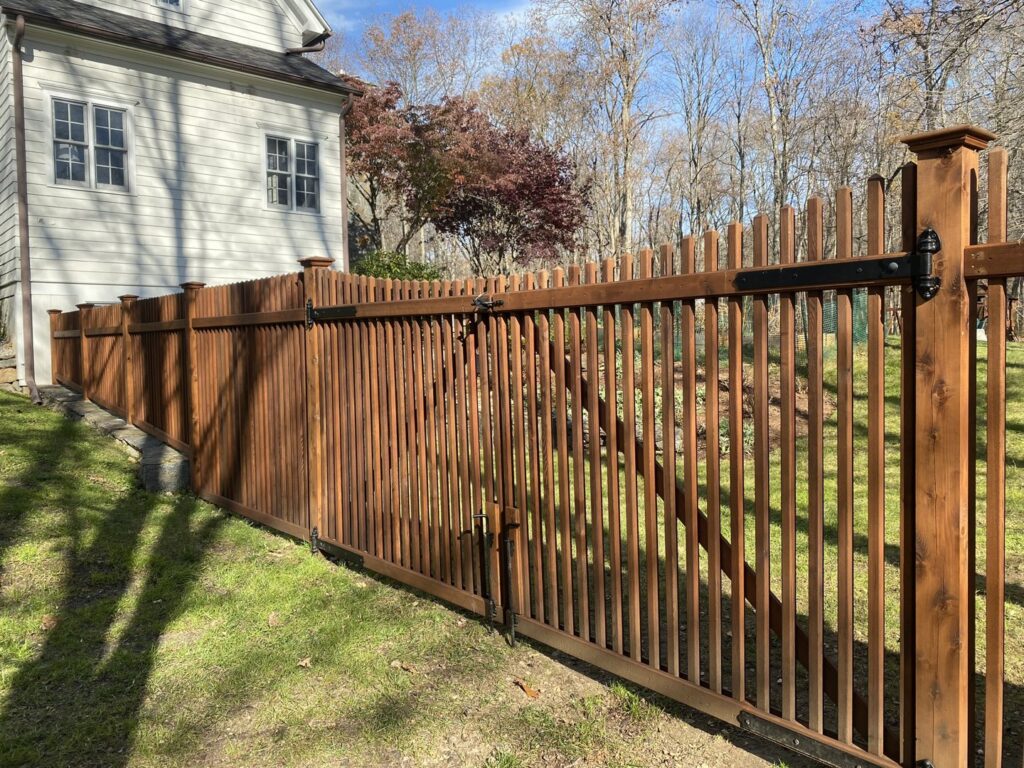 A classic wooden picket fence with a gate, providing security and charm from Flanagan Fencing in Brookfield, CT.
