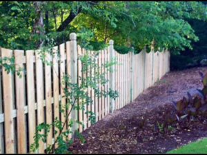 A classic wooden picket fence enhancing a landscaped garden by Integrity Construction and Fencing, LLC in Clanton, AL.