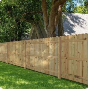 A classic wooden picket fence installed in a green residential yard by JBunlimitedfencingllc in Savannah, GA.