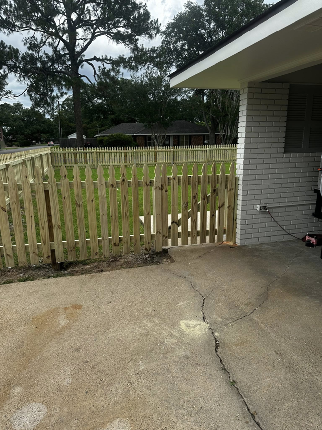 A newly installed wooden picket fence with a gate next to a patio area by J&L Fence in Zolfo Springs, FL.