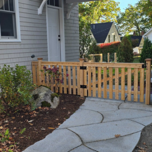 A newly installed wooden picket fence with a gate leading to a home by Midcoast Fence in Northport, ME.