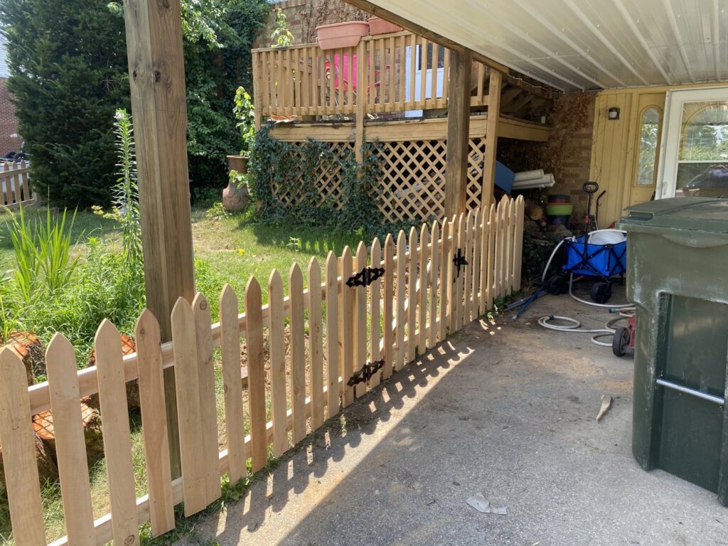 A charming wooden picket fence with a gate, expertly installed by Petty Fence Company LLC in Evansville, IN.