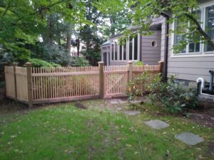 A charming wooden picket fence with a gate installed next to a home by Reilly Fence Inc in Cranston, RI.