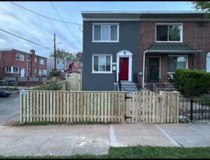 A newly installed wooden picket fence with a gate in front of a townhouse by AFK FENCE LLC in Waldorf, MD.