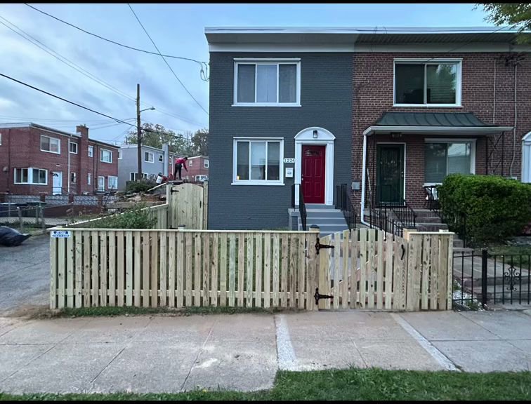 A newly installed wooden picket fence with a gate in front of a townhouse by AFK FENCE LLC in Waldorf, MD.