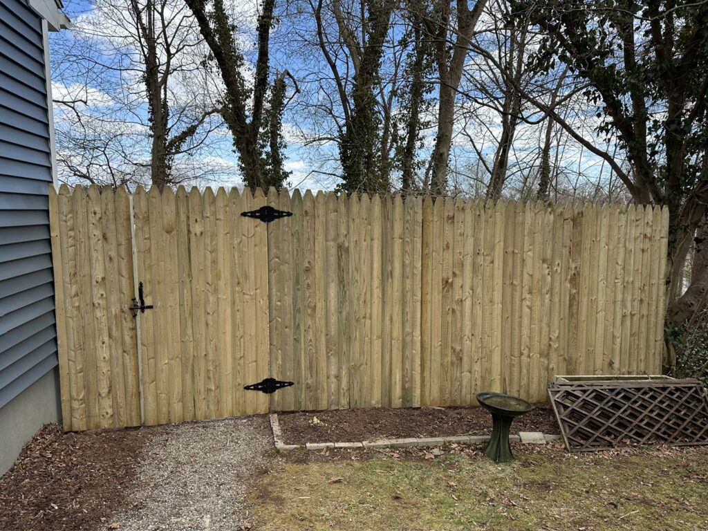 A classic wooden picket fence with a gate installed by White Eagle Fence Inc in New Haven, CT.