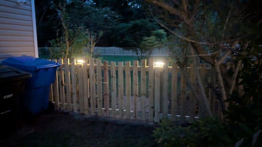 A wooden picket fence with solar lights installed at night by Gifford Contracting & Repair - Custom Privacy Fencing in Goose Creek, SC.