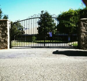 A charming wooden picket gate at a driveway entrance, decorated with ribbons, installed by The Fence Company in Fresno, CA.