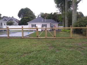 A sturdy wooden fence with a gate enclosing a pool area, installed by Reilly Fence Inc in Cranston, RI.