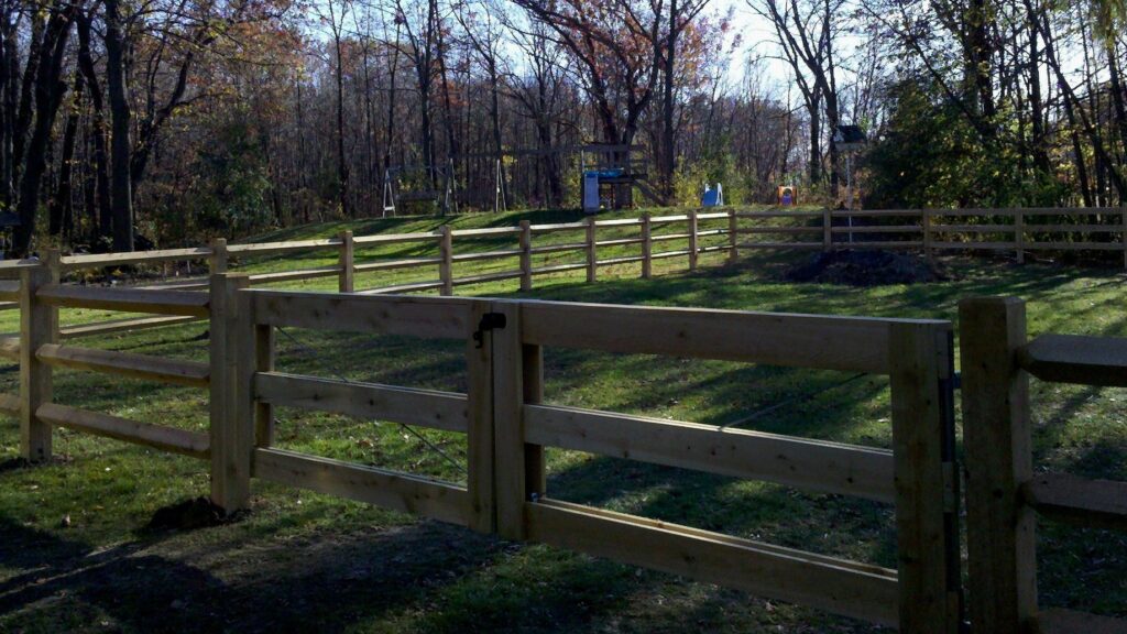 A newly installed wooden post-and-rail fence with a gate by Statewide Fencing, Inc. in Franksville, WI