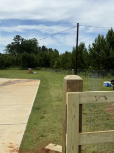 A wooden post and wire mesh fence installation along a property line by G2 Home Solutions in Phenix City, AL.