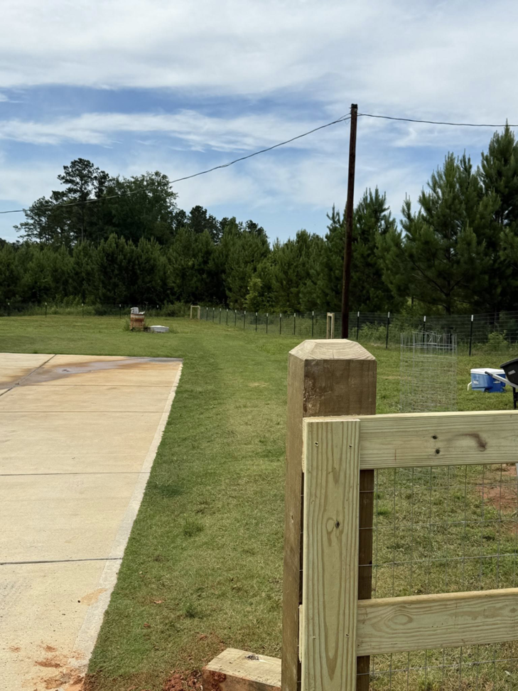 A wooden post and wire mesh fence installation along a property line by G2 Home Solutions in Phenix City, AL.