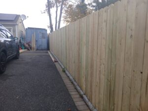 A sturdy wooden privacy fence installed along a residential driveway by Zelaya Fence in New York City, NY.