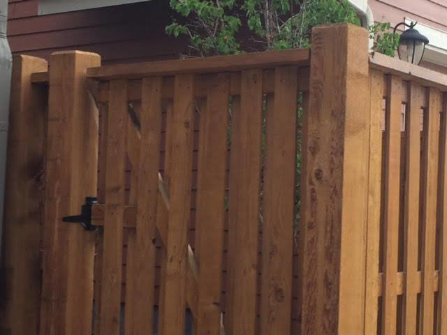 A close-up view of a sturdy wooden privacy fence with a matching gate, built by Colorado Fence and Gate Systems in Colorado Springs, CO.