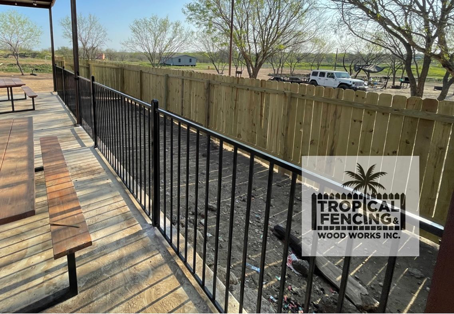 A newly installed wooden privacy fence and black metal railing by Tropical Fencing And Wood Works in Page, TX.