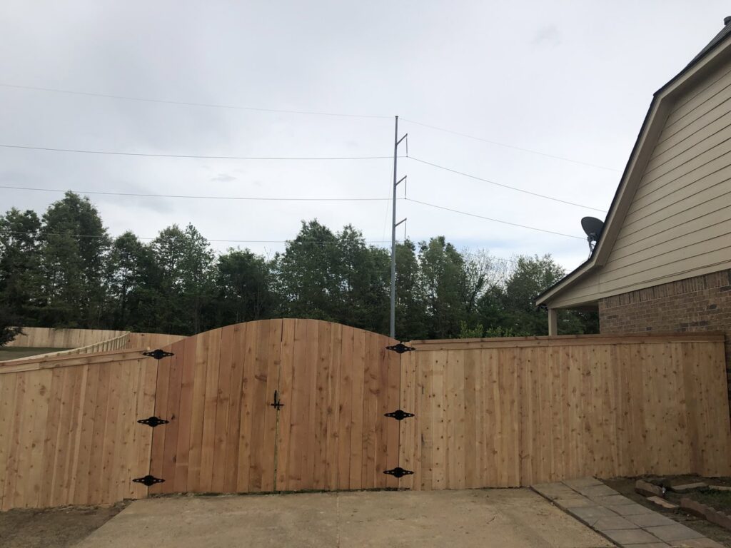 A new wooden privacy fence with an elegant arched gate installed by First Responder Outdoor Construction LLC in Bartlett, TN.
