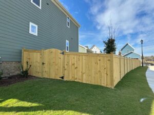 A newly installed wooden privacy fence with an elegant arched gate next to a home by Limitless Boundaries LLC in Garner, NC.