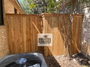 A newly installed wooden privacy fence concealing an AC unit next to a house by Tropical Fencing And Wood Works in Page, TX.