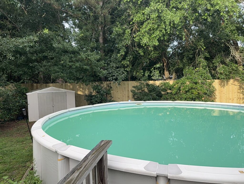 A newly installed wooden privacy fence surrounding an above-ground swimming pool by Riggins Renovations LLC in Biloxi, MS.