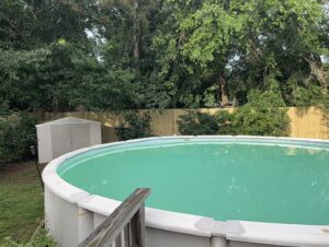 A newly installed wooden privacy fence surrounding an above-ground swimming pool by Riggins Renovations LLC in Biloxi, MS.
