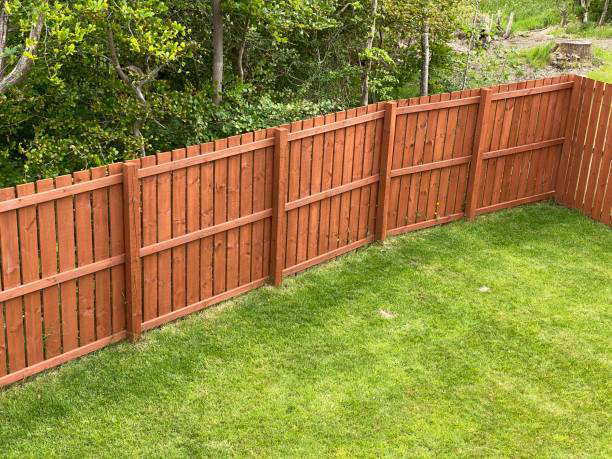 A newly installed wooden privacy fence enclosing a green backyard, a service provided by Delmarva Facility Maintenance Services in Laurel, DE.