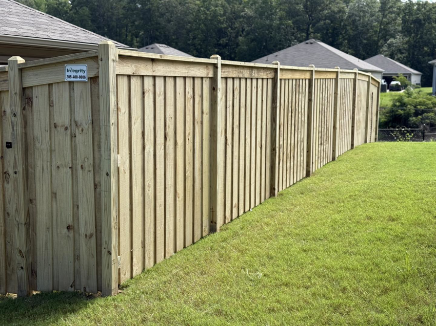 A sturdy wooden privacy fence installed in a green residential backyard by Integrity Construction and Fencing, LLC in Clanton, AL.