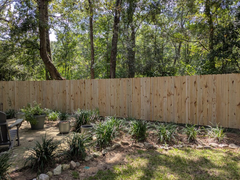 A wooden privacy fence installed in a backyard with potted plants and landscaping by Superior Fence & Rail of North Shore in Gulfport, MS.