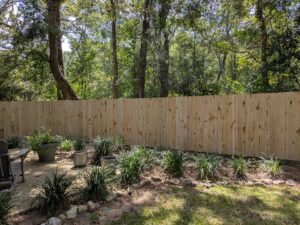 A wooden privacy fence installed in a backyard with potted plants and landscaping by Superior Fence & Rail of North Shore in Gulfport, MS.