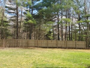 A tall wooden privacy fence installed in a backyard, providing seclusion for a home in Weare, NH by MH Fence.