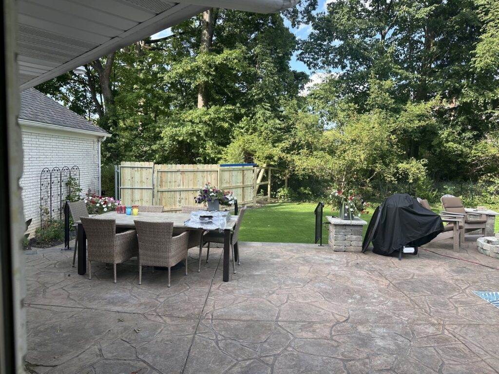 A wooden privacy fence installed in a backyard with a stone patio by Affordable Fencing in Parma, OH.