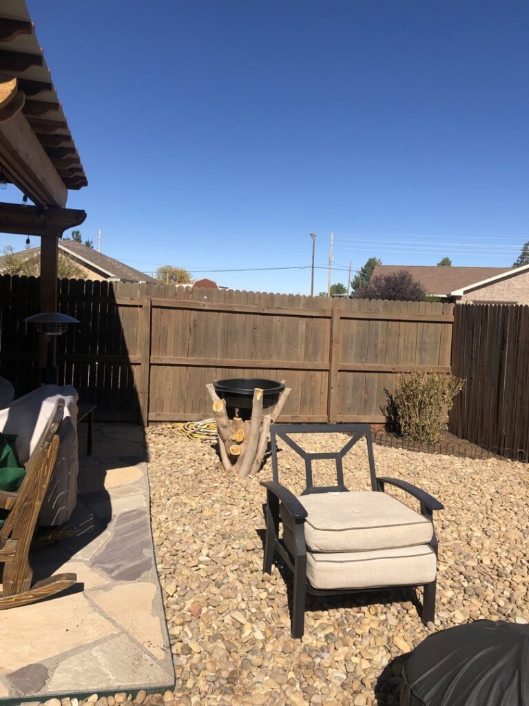 A sturdy wooden privacy fence enclosing a backyard patio area with outdoor furniture, built by DC Fencing LLC in Clovis, NM.