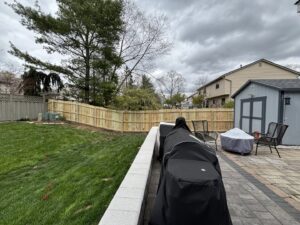 A new wooden privacy fence installed in a backyard with a stone patio, by D&M Renovation Services LLC in Columbus, OH.