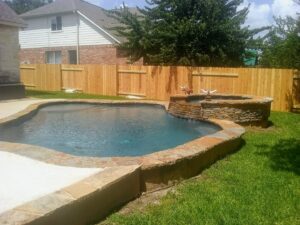 A wooden privacy fence enclosing a backyard with a swimming pool by Landmark Fence & Deck Company in Saint Paul, MN.