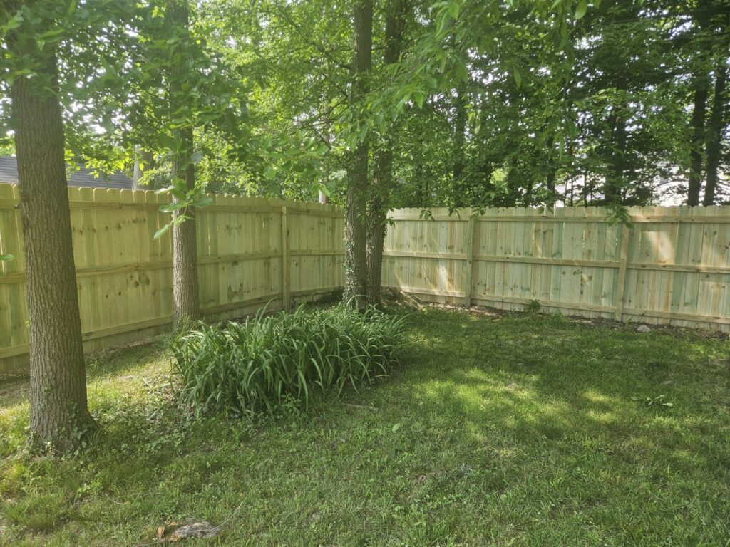 A wooden privacy fence installed in a backyard surrounded by trees by Affordable Fencing in Parma, OH.