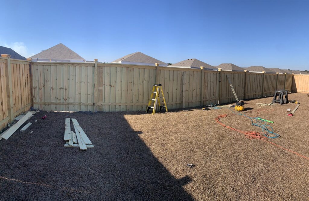 A wooden privacy fence installed in a backyard with construction tools nearby by Heavenly Gates Construction LLC in Miami, FL