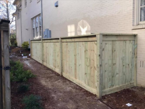 A durable wooden privacy fence installed along the side of a brick house by Integrity Construction and Fencing, LLC in Clanton, AL.