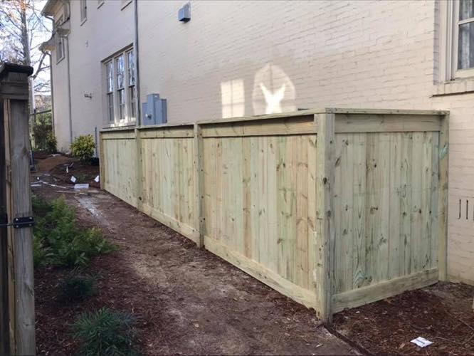 A durable wooden privacy fence installed along the side of a brick house by Integrity Construction and Fencing, LLC in Clanton, AL.
